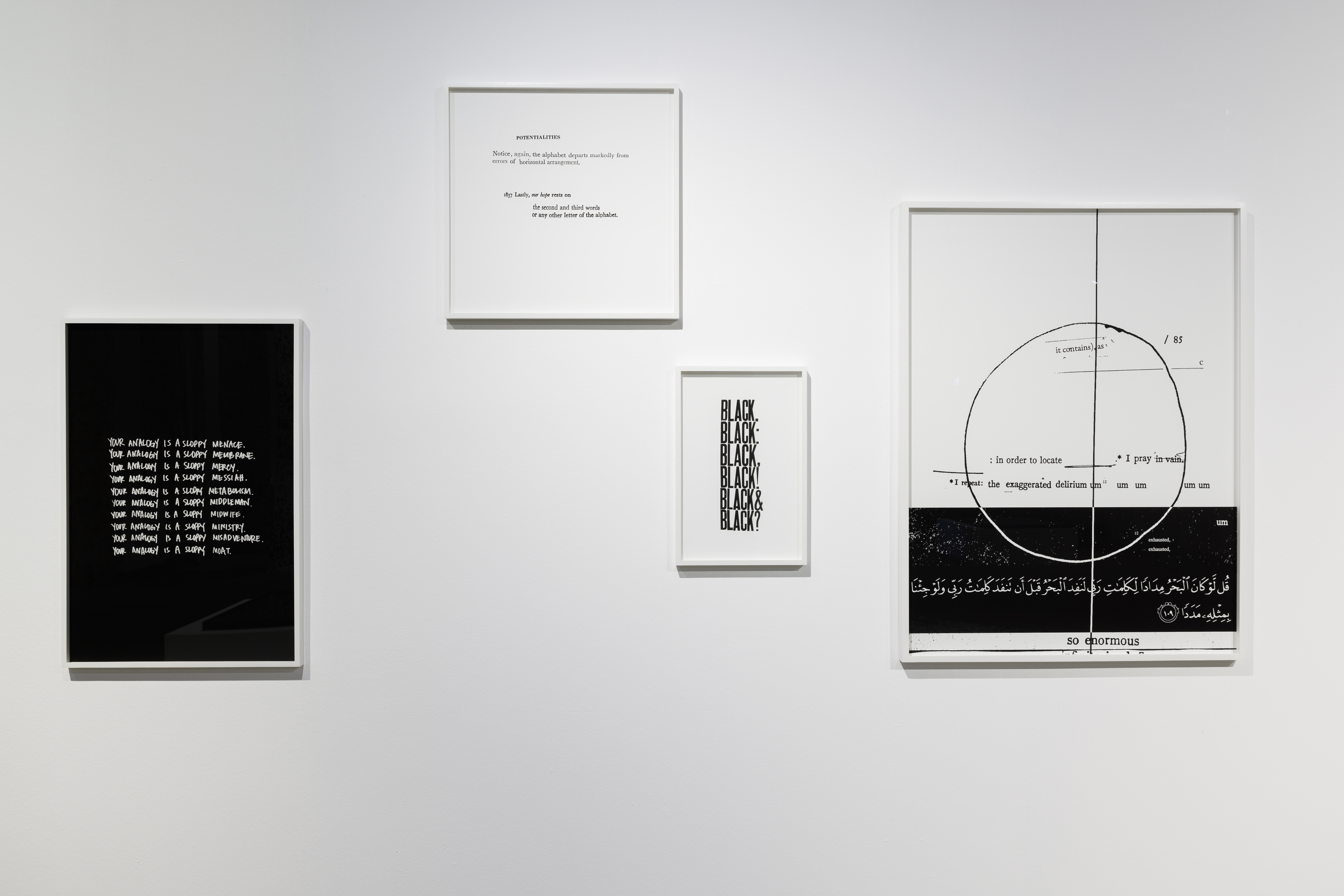Four black-and-white text works hang at different heights. Small repeated lines and stacked words sit beside a larger diagram of an outlined circle crossed by vertical and horizontal lines.